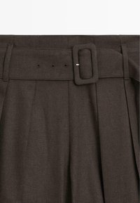 Pantaloni marrone scuro con una cintura larga dotata di una fibbia rettangolare, design frontale con pieghe e tessuto testurizzato.