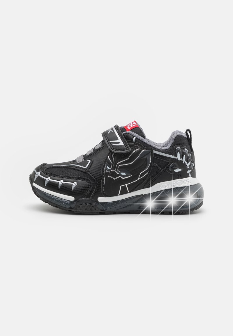 Sorte sneakers med en tekstureret overdel, prydet med et grafisk design af en maske og hånd, Velcro-strop og lysende accenter på sålen.