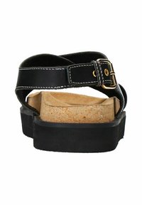 Sandale en cuir noir avec semelle en liège, sangle ajustable avec boucle dorée et semelle en caoutchouc texturé noir.