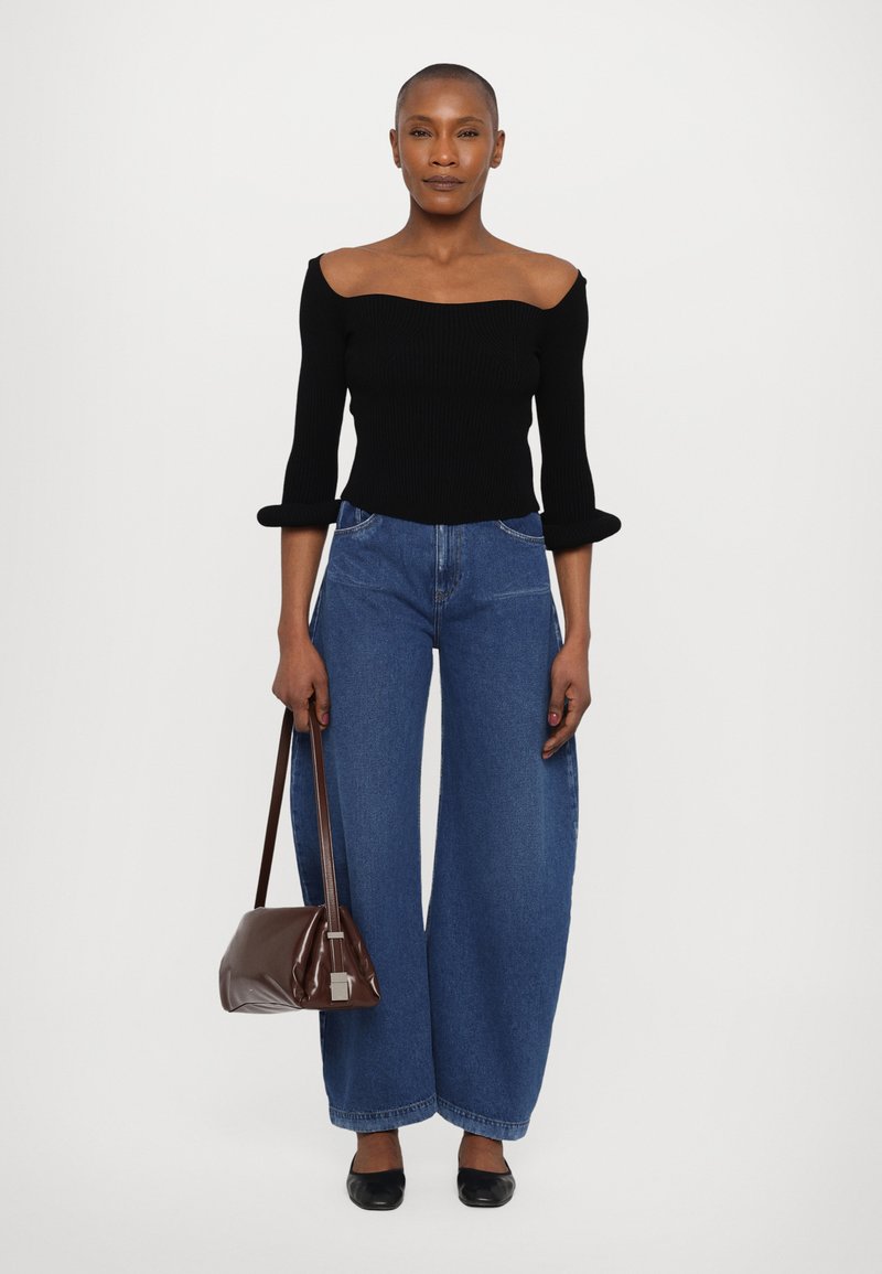 Black ribbed off-shoulder top, wide blue denim jeans, brown handbag, and black flats. The jeans feature a high waist and loose fit.