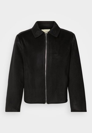 Crna jakna na patent napravljen od mekanog tkanja. Ima špicastu kragnu i reljefne detalje na kragni. Rukavi su ravno rezani s minimalnim dizajnom.