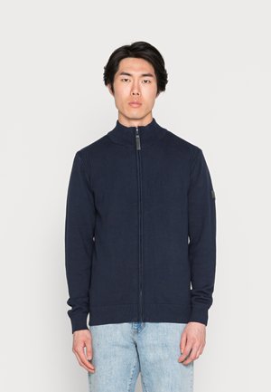 Maglione zip-up navy in tessuto a maglia, con colletto alto, polsini a coste e un leggero dettaglio del logo sulla manica sinistra.