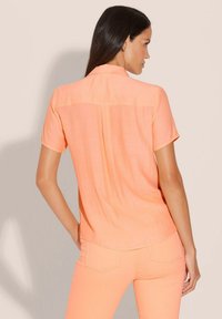 Korte mouwen, knoopsluiting shirt van licht perzik stof met een gladde textuur, met een achterpand en een gebogen zoom.