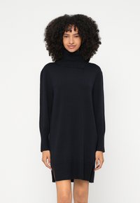 Vestido de gola alta em malha na cor azul-marinho escuro, com mangas compridas, punhos canelados, fendas laterais e um corte descontraído.