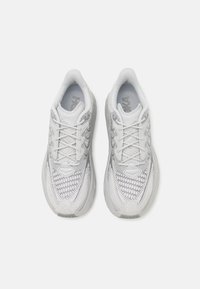 Chaussures de sport blanches avec une tige en mesh texturé, des accents argentés et une semelle rembourrée. Dotées de lacets et d'un col rembourré pour un meilleur maintien.