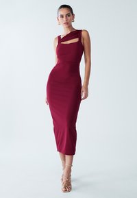 Burgundinio atspalvio aptempta suknelė su viena pečių linija, išpjova ir raukiniais. Lygi audinys su aptakiu, kūną pabrėžiančiu siluetu.