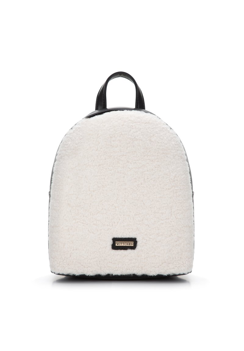Bílý batoh z umělé kožešiny s kulatým tvarem, černými koženými akcenty a zlatou logem na přední straně. Dvojité horní rukojeti pro nošení.