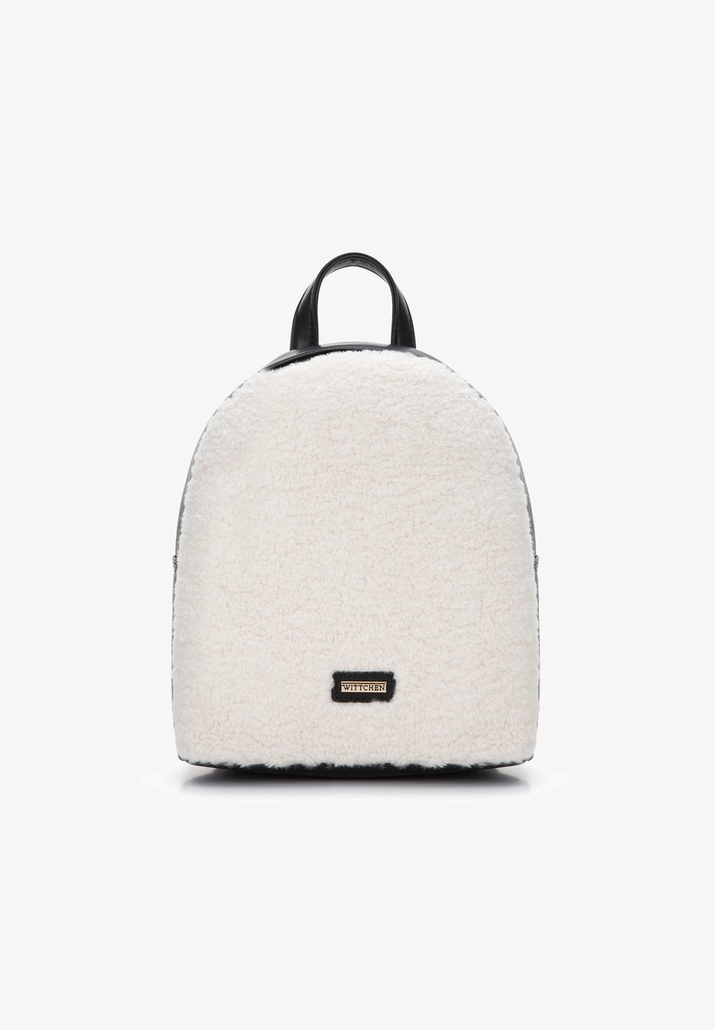 Mochila de piel sintética blanca con forma redondeada, detalles en cuero negro y una placa de logo dorado en la parte delantera. Tiene dos asas en la parte superior para llevar.