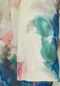 Tissu transparent présentant un motif aquarelle abstrait dans des nuances de sarcelle, rose et vert, avec un élastique à l'ourlet des manches.