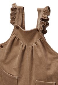 Salopette en velours côtelé marron avec des bretelles volantes, deux poches avant et des détails en boutons. Tissu texturé avec des lignes verticales.
