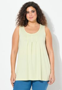Top senza maniche di un giallo chiaro con scollatura a giro, dettagli plissettati sul davanti e tessuto morbido, abbinato a pantaloni teal.