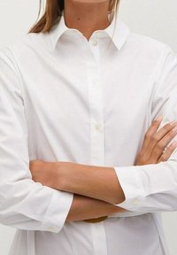 Weißes Hemd aus leichtem Stoff, mit klassischem Kragen, langen Ärmeln und mit Knöpfen versehenen Manschetten. Schlichtes Design, ohne Muster.