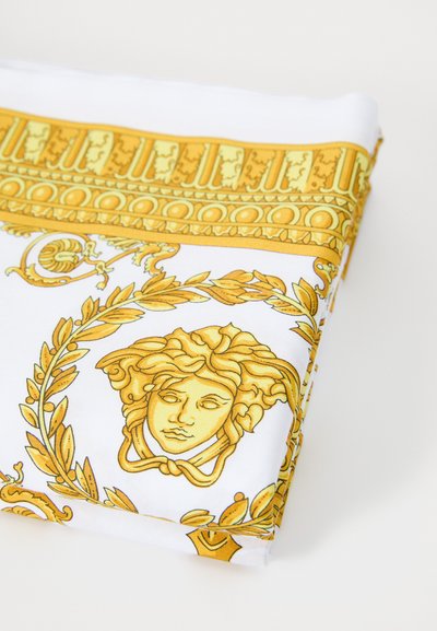 Material alb cu modele aurii complexe, inclusiv o cap meduză centrală, elemente florale și borduri decorative.