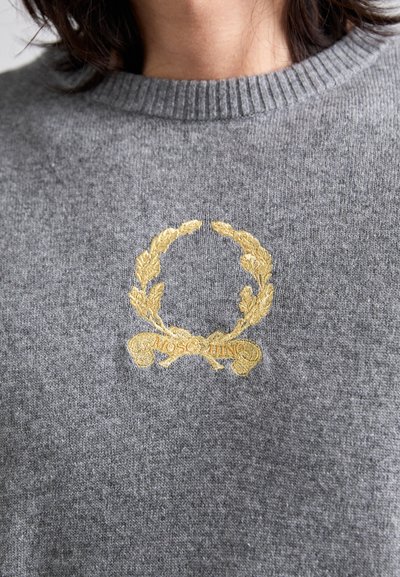 Grauer Strickpullover mit einem geribbelten Rundhalsausschnitt und einem goldfarbenen gestickten Lorbeerkranz mit dem Text "MOSCHINO" in der Mitte.