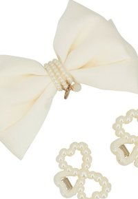 Clip in tessuto avorio a forma di fiocco con dettagli in perla, caratterizzato da una consistenza morbida e una banda centrale di perline perla. Include due fermagli per capelli a forma di cuore.