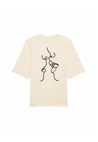 Krémové tričko z měkké látky, s černým kresleným vzorem abstraktních tváří na zadní straně. Volný střih s krátkými rukávy.