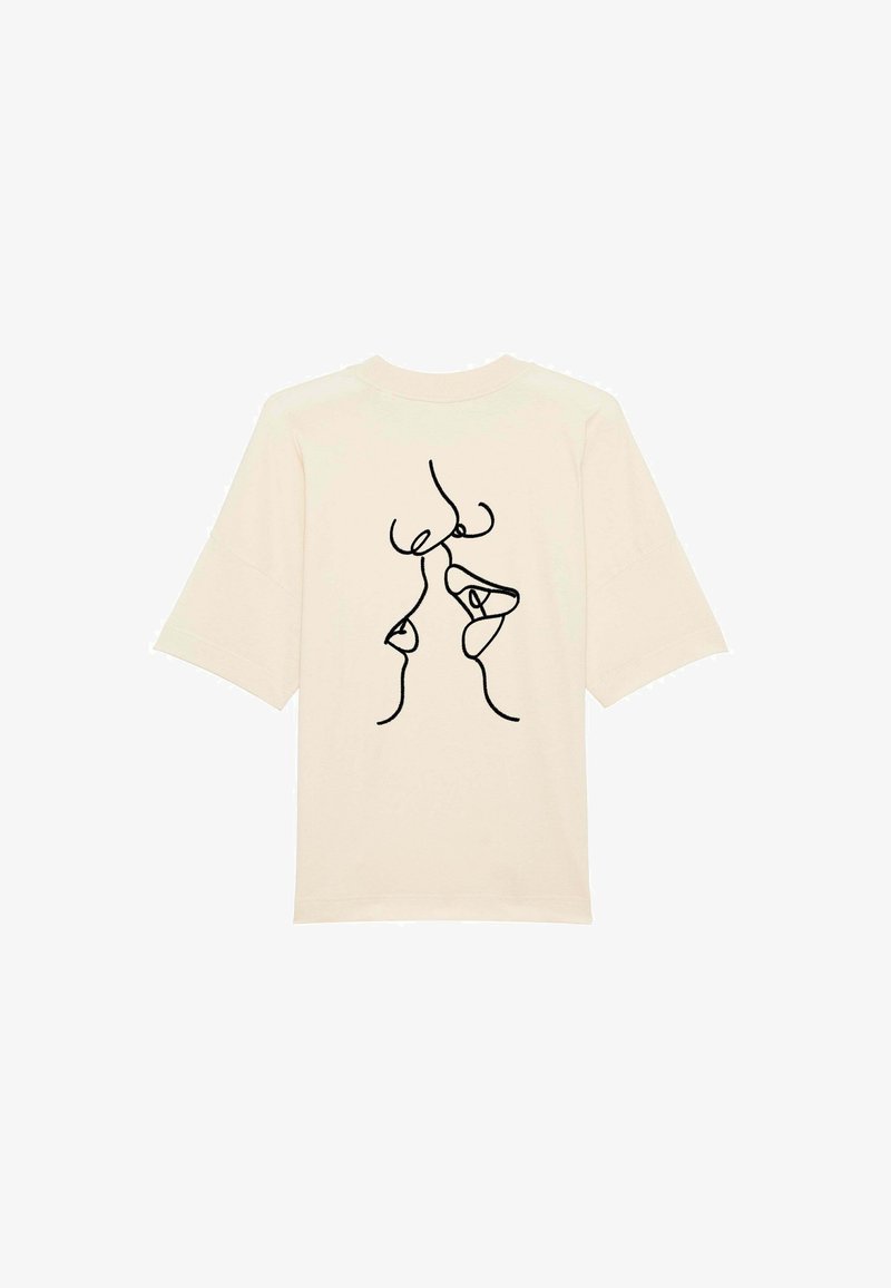 Krémové tričko z měkké látky, s černým kresleným vzorem abstraktních tváří na zadní straně. Volný střih s krátkými rukávy.