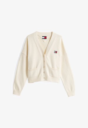 Gilet en tricot crème avec un col en V, quatre boutons, deux poches frontales et une paire de logos sur le côté gauche. Il présente des poignets et un ourlet côtelés.