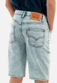 Helleblaue Denimshorts mit entspannter Passform, sichtbaren Nähten und einem Lederpatch mit Branding am hinteren Bund, zwei Gesäßtaschen.
