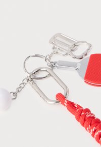 Porte-clés avec un mousqueton argenté, un sifflet rouge et un cordon tressé rouge. Comprend une perle ronde blanche et des accessoires supplémentaires pour porte-clés.