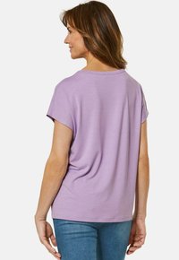 Paarse T-shirt met korte mouwen, relaxed fit en een ronde halslijn, gemaakt van zacht materiaal en met een minimalistisch ontwerp. Draagt met een blauwe spijkerbroek.