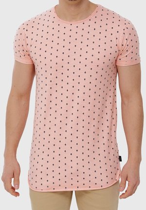 Tričko s krátkým rukávem a kulatým výstřihem v broskvové barvě s texturovaným povrchem, zdobené opakujícím se černým vzorem diamantů po celém povrchu.