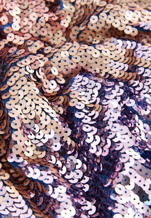 Țesătură cu paiete rotunde în culoarea roz auriu și roz pe un fundal închis, creând o suprafață texturată și reflectorizantă.