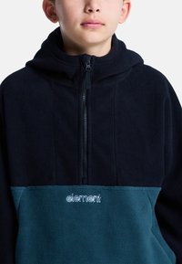 Half-zip fleecetrui in marineblauw en teal. Gemaakt van zachte stof, met een capuchon en geborduurd "element" logo op de borst.