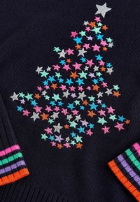 Blå stickad tröja med färgglada broderade stjärnor i rosa, grön och orange som bildar en julgransform, med randiga muddar.