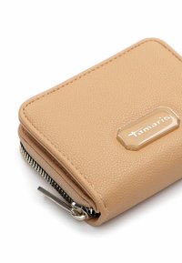 Tan leather wallet with a textured surface, featuring a gold-tone logo plate, zip closure, and black zipper detailing.