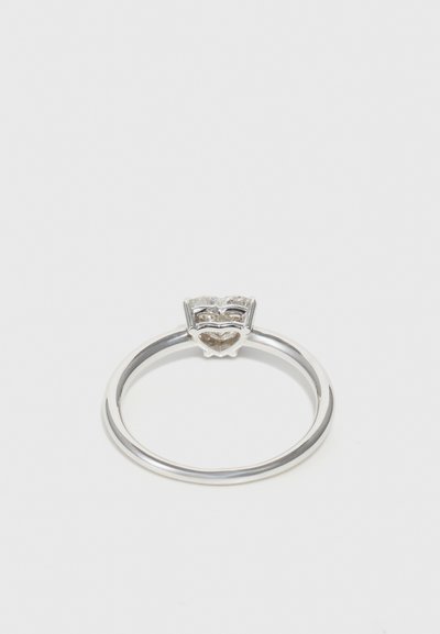 Anillo de plata con un acento en forma de corazón y una superficie texturizada, colocado sobre una banda pulida. Diseño simple sin adornos adicionales.