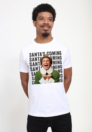 Hvid bomulds T-shirt med et stort grafisk motiv af en karakter i en grøn dragt med hvide pelsdetaljer, omgivet af gentaget tekst "JULENISSE KOMMER."