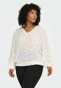 Bijela prozirna bluzica s cvjetnim uzorkom, V-izrezom, dugim rukavima i mekim, plišanim rubom; uparena s crnim tajicama koje lijepo prate tijelo.