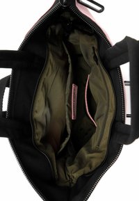 Bolsa de tela negra con interior rosa, cierre de cremallera, bolsillos interiores y textura suave. Las correas se extienden desde la parte superior para llevarla.