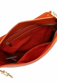 Interno di una borsa in pelle arancione con una texture liscia, dotato di una tasca con zip e due scomparti aperti, foderato in tessuto coordinato.