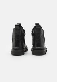 Czarne botki za kostkę z teksturowanej skóry, o zaokrąglonym nosku, z elastycznym bocznym panelem i pętlą do zakładania. Gruba gumowa podeszwa dla lepszej przyczepności.