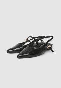 Schwarze Lackleder-Slingback-Schuhe mit spitzer Zehenpartie, überkreuztem Riemendesign und goldfarbenen Hardware-Akzenten.