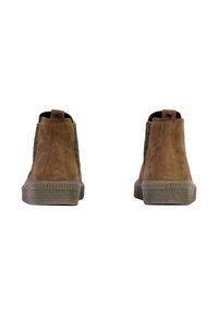 Bottes chelsea en daim marron avec des panneaux latéraux texturés, bout rond, et une semelle en caoutchouc dotée de rainures horizontales. Tirette à l'arrière incluse.