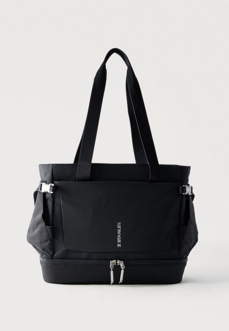 Μαύρη τσάντα πολλαπλών τσεπών με μακριές λαβές, μπροστινό καπάκι, πλαϊνά κλιπ και φερμουάρ στον κάτω διαμέρισμα, λογότυπο "Stanley" στο μπροστινό μέρος.