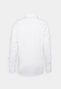 Weißes Langarmhemd aus Baumwolle mit Standardkragen, Knopfmanschetten und geradem Saum; glatte Textur ohne sichtbare Muster.