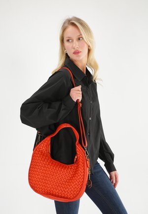 Rote Lederhandtasche mit gewebter Textur, geschwungener Form und abnehmbarem Schulterriemen. Glatte Oberfläche und Reißverschlussverschluss.