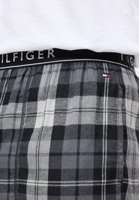 Szürke és fekete kockás boxeralsó fekete rugalmas derékkal, melyen fehér betűkkel a "GILFIGER" logo található. Pamut anyag, kockás minta.