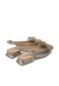 Scarpe slingback metalliche dorate con tacco quadrato piatto, decorazione a fiocco impreziosita da dettagli gioiello, superficie liscia e punta arrotondata.