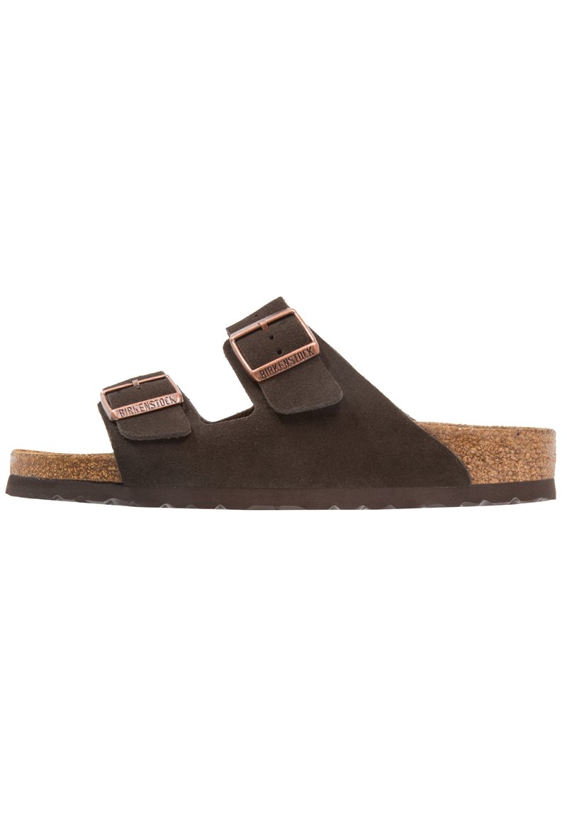 Ciabatte in suede marrone con due cinturini regolabili, fibbie color rame e un sottopiede in sughero. Suola piatta con design della trama testurizzato.