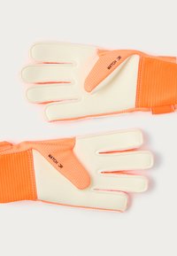 Guantes de portero de fútbol en color naranja con palmas de látex blanco, puntas de los dedos texturizadas y una correa de muñeca acolchada. "MATCH JR" está impreso en el lateral.