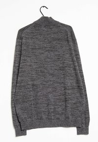 Grå sweater med ribbet krave og manchetter, prydet med et struktureret, space-dyed mønster. Hænger på en sort krog mod en hvid baggrund.