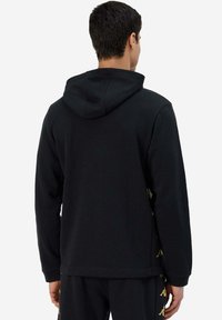 Felpa nera con cappuccio e maniche lunghe, caratterizzata da una texture liscia e dettagli dorati sui lati. Vestibilità casual, stile a pullover.