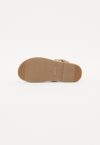 Sandal såle i et lysebrunt gummimateriale med et strukturert grep mønster, med en avrundet form og lett bue for støtte.