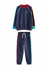 Felpa navy con ricami a arco iris, colletto rosso e strisce colorate ai lati. Pantaloni navy abbinati con tasche e cordoncino, accentuati da colori multipli.