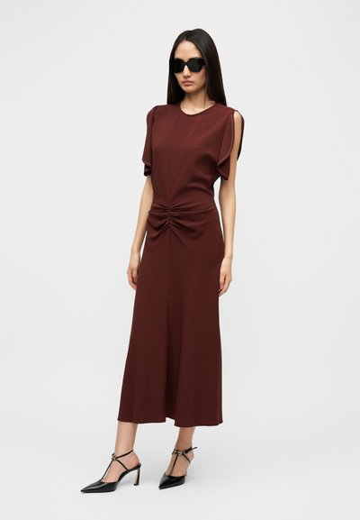 Μίντι φόρεμα βυσσινί με κοντά φουσκωτά μανίκια, ζαρτιέρες στη μέση και άνετη εφαρμογή. Συνδυασμένο με μαύρες γόβες μυτερές.